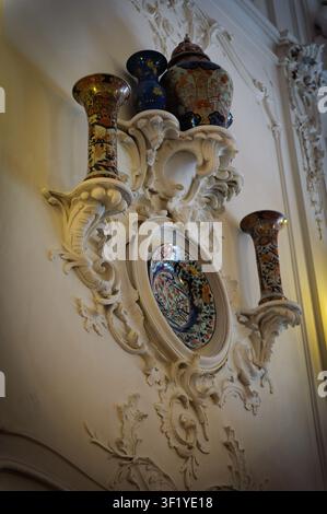 Uno scaffale montato a muro bianco e decorato che mostra vasi e piatti decorativi. Foto Stock