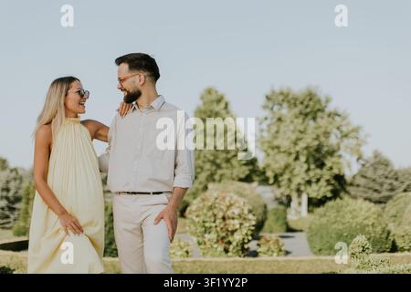 Una coppia si gode un momento allegro in un giardino lussureggiante, scambiandosi sorrisi e calore. Foto Stock