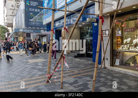 Scena di strada a Tsim Sha Tsui, Hong Kong, impalcatura di bambù eretta sul marciapiede fuori da un negozio commerciale Foto Stock