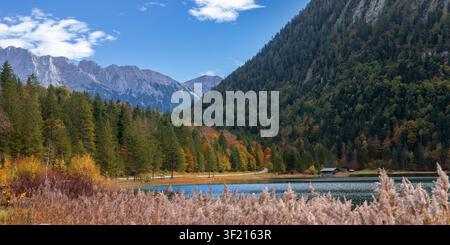 Il lago Ferchensee che riflette una foresta autunnale con montagne e cielo azzurro a Mittenwald, Germania Foto Stock