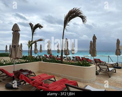 Sedie e ombrelloni che si affacciano sull'oceano in un resort a Cancún, Messico, in una tempestosa giornata invernale. Foto Stock