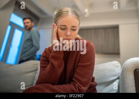 Donna seduta sul divano che si sente infelice e triste dopo una lite domestica emotiva con il partner Foto Stock