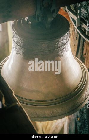 Campana d'epoca con intricati intagli metallici appesa all'interno di un antico campanile in legno Foto Stock