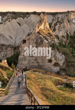 Göreme, Cappadocia, Turchia – 06 settembre 2025: Turisti che camminano su un sentiero di legno al Museo all'aperto di Göreme a Cappadocia, caratterizzato da antiche abitazioni rupestri e formazioni rocciose a camino delle fate Foto Stock