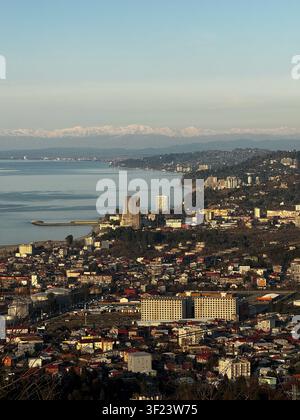 Vista aerea scenografica della costa di Batumi e del paesaggio urbano con le montagne innevate del Caucaso sullo sfondo Foto Stock