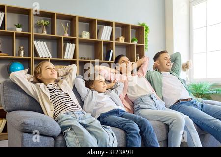 Famiglia felice con genitori e bambini che si rilassano insieme sul divano a casa Foto Stock