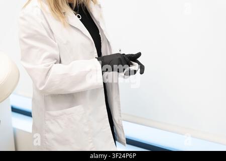 Operatore sanitario con guanti e camice da laboratorio che prepara un'iniezione in clinica Foto Stock