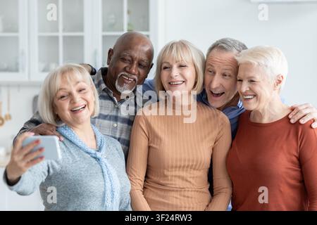 Gruppo diversificato e felice di cinque adulti che sorridono insieme mentre scattano un selfie a casa, concetto di perdita di peso Foto Stock