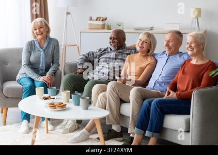 Anziani felici che godono insieme di un film in un soggiorno luminoso, concetto di connessione familiare Foto Stock