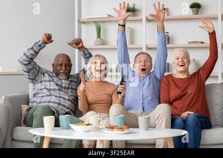 Gruppo diversificato e felice di anziani che celebrano insieme a casa, incontro indoor gioioso Foto Stock