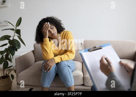 Donna nera preoccupata che discute della salute mentale con un terapeuta in ufficio, concetto di assistenza sanitaria Foto Stock