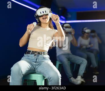 Ragazza con occhiali per realtà virtuale sta giocando a un videogame Foto Stock
