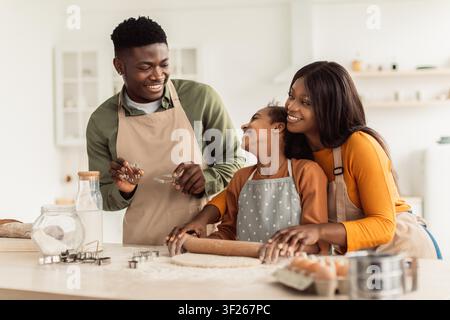 Famiglia che cucina insieme in cucina, genitori e bambino sorridenti si divertono Foto Stock