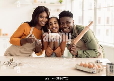 Famosa famiglia afroamericana che cuoce insieme in cucina, sorridendo e divertendosi Foto Stock