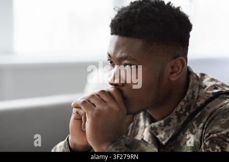 Soldato maschio concentrato immerso nei suoi pensieri, ambiente d'ufficio militare, concetto di benessere mentale Foto Stock