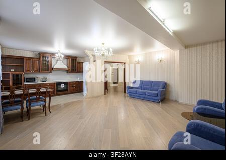 interno spazioso e ben illuminato con cucina aperta, zona pranzo e soggiorno. La tavolozza di colori include marrone, blu e beige Foto Stock