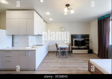 monolocale ben illuminato con cucina moderna, zona pranzo e centro multimediale con TV Foto Stock
