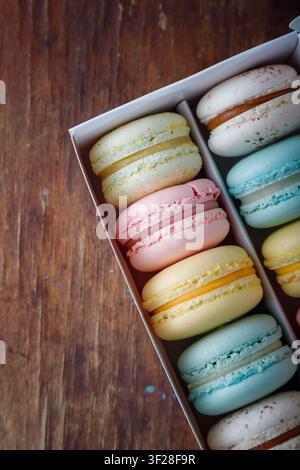 Macaroni multicolori in scatola bianca su sfondo di legno antico. Spazio di copia. Vista dall'alto Foto Stock