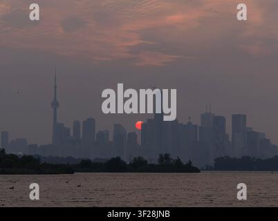 Toronto, Canada. 16 luglio 2026. Il tramonto è visibile mentre il fumo degli incendi avvolge Toronto, Canada, il 16 luglio 2026. Gli incendi che hanno devastato il nord-ovest dell'Ontario, Canada, negli ultimi giorni hanno causato un forte smog e un netto peggioramento della qualità dell'aria in diverse regioni, tra cui Ottawa, la capitale del paese, e Toronto, la città più grande del Canada. Credit: Zou Zheng/Xinhua/Alamy Live News Foto Stock