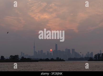 Toronto, Canada. 16 luglio 2026. Il tramonto è visibile mentre il fumo degli incendi avvolge Toronto, Canada, il 16 luglio 2026. Gli incendi che hanno devastato il nord-ovest dell'Ontario, Canada, negli ultimi giorni hanno causato un forte smog e un netto peggioramento della qualità dell'aria in diverse regioni, tra cui Ottawa, la capitale del paese, e Toronto, la città più grande del Canada. Credit: Zou Zheng/Xinhua/Alamy Live News Foto Stock