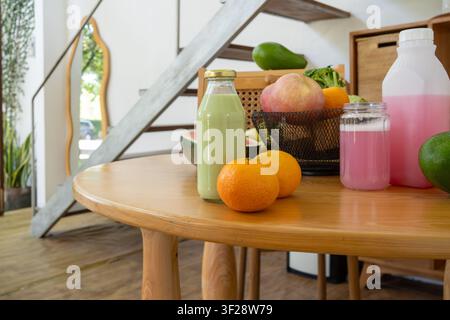 Bevande salutari fatte in casa con frutti freschi esposti su un tavolo di legno in un interno moderno e luminoso. Foto Stock