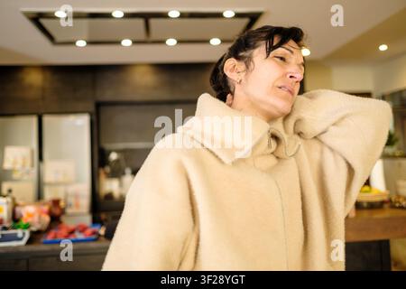 Donna che sente disagio, si strofina le spalle e il collo a causa del dolore Foto Stock