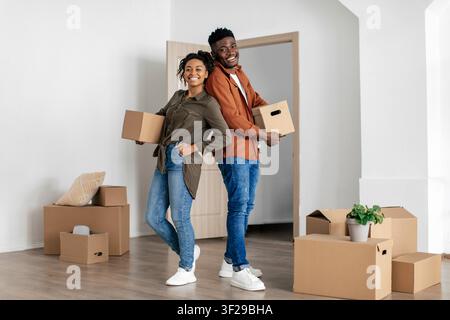 Giovane coppia afroamericana felice che disimpaca scatole nella nuova casa, concetto di trasloco Foto Stock