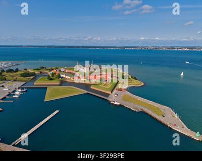 Vista aerea del castello di Kronborg, una fortezza storica circondata da fossati e bastioni verdi, situata sulla costa con un porto e il mare blu sotto un c Foto Stock