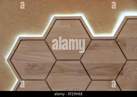Pannello murale esagonale in legno con retroilluminazione a LED, design a nido d'ape illuminato per pareti moderne Foto Stock