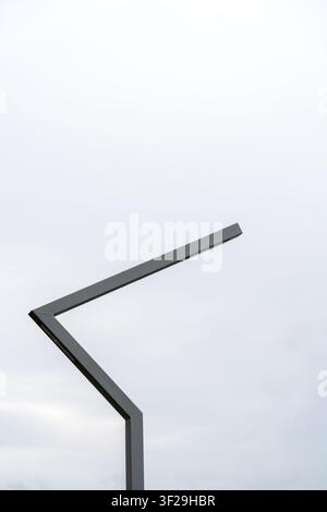 Palo lampada da strada moderno contro un cielo nuvoloso, design minimalista di illuminazione esterna, vista da basso angolo Foto Stock