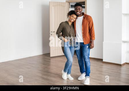 Coppia nera felice che si abbraccia e sorride in un nuovo appartamento, concetto di casa Foto Stock