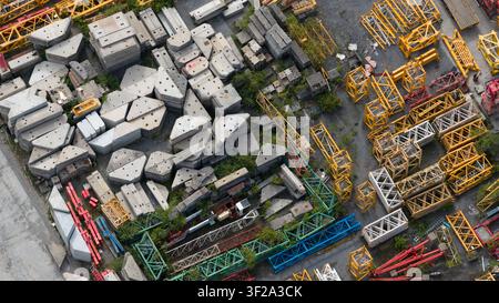 Vista aerea di un cantiere di stoccaggio pieno di blocchi di cemento e varie sezioni di tralicci di gru a Seneffe, Vallonia, Belgio. Foto Stock