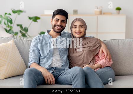 Giovane coppia felice che si abbraccia sul divano a casa, concetto di stile di vita multiculturale Foto Stock