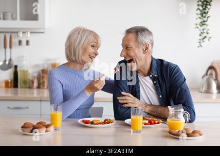 Felice coppia caucasica anziana che gode della colazione insieme in una cucina moderna Foto Stock
