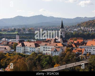 Una vista aerea mostra Kranj, in Slovenia, con la sua vecchia città medievale, le torri delle chiese e il paesaggio circostante. Un cielo blu terso evidenzia la scena. Foto Stock