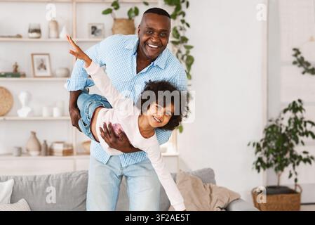 Divertimento in famiglia. Felice nonno afroamericano che gioca a stupido gioco con sua nipote a casa, spazio vuoto Foto Stock