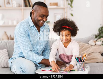 Passatempi di famiglia. Nonno Africano Americano e sua bella nipote che si riuniscono a casa Foto Stock