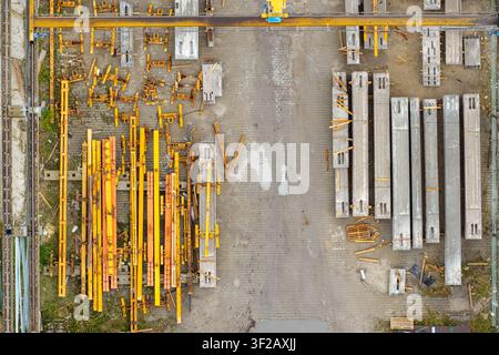 Vista aerea di elementi in cemento precompresso e telai di costruzione in metallo giallo disposti in un deposito in Polonia. Foto Stock