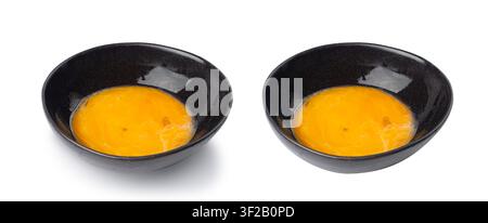 Tuorli d'uovo sbattuti in ciotola, uova di pollo fresche per ricetta di cucina, tuorli biologici misti in ciotola nera Foto Stock