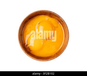 Tuorli d'uovo sbattuti in una ciotola, uova di pollo fresche per ricetta di cucina, tuorli organici mischiati in una ciotola di legno Foto Stock