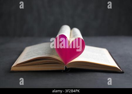Libro con un cuore fatto di pagine sul tavolo Foto Stock