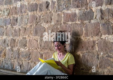 Donna che scrive appunti felici in un quaderno giallo Foto Stock