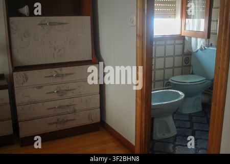 Una foto dell'interno di una camera da letto di un appartamento classico con un armadio scrivania in legno vintage con cassetti floreali. Un'apertura in legno rivela un retro Foto Stock