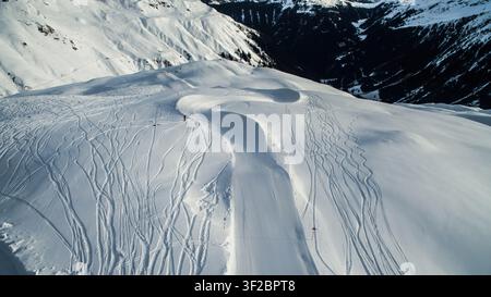 Vista aerea del comprensorio sciistico di Watles con piste preparate e numerose tracce di sci incise nella neve fresca sulle vette delle montagne a Mals, Trentino Foto Stock