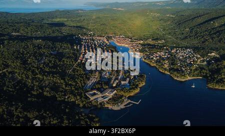 Vista aerea che mostra la città vecchia di Hvar, isola di Hvar, Croazia. Paesaggio costiero mediterraneo con barche, porto e vegetazione rigogliosa Foto Stock