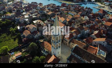 Veduta aerea che mostra il campanile della chiesa di San Stefano in mezzo agli edifici tradizionali con tetti rossi a Stari Grad, Hvar Foto Stock