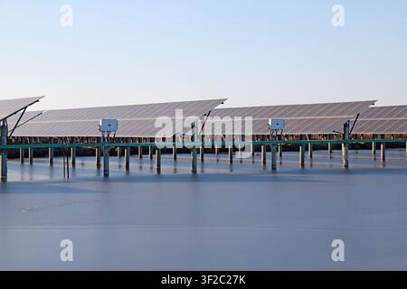 Questa fotografia mostra una serie di pannelli solari installati su una centrale galleggiante. Pannelli solari blu scuro ordinatamente disposti sono montati su cemento Foto Stock