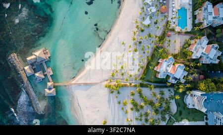 Vista aerea della località balneare con bungalow sull'acqua, sabbia bianca, palme e piscine a Juan Dolio, San Pedro de Macoris, Repubblica Dominicana Foto Stock