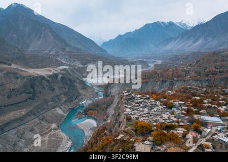 Vista aerea del forte storico di Altit arroccato su una scogliera che si affaccia sul fiume turchese di Hunza, circondato da fogliame autunnale e montagne drammatiche Foto Stock