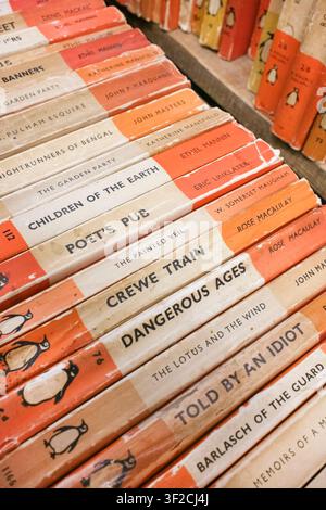 Scaffali di narrativa vintage Penguin con dorsi codificati arancioni Foto Stock